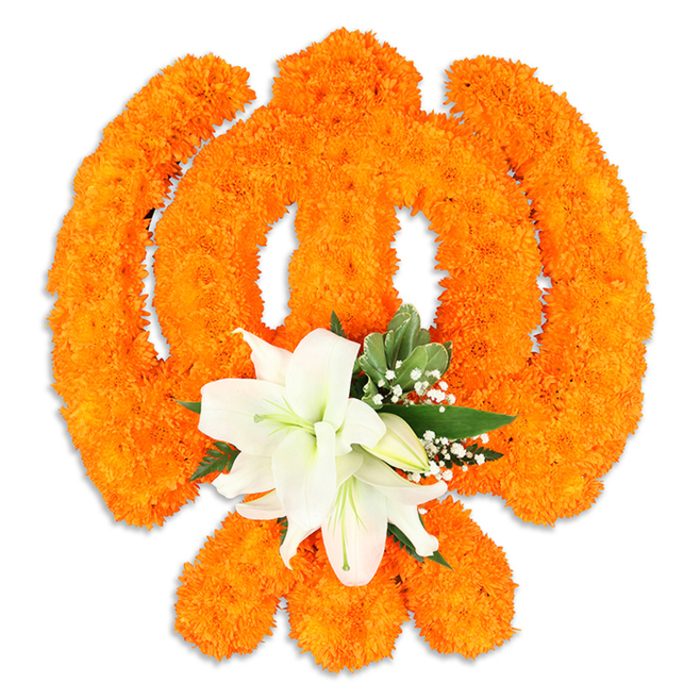 A composed floral Ik Onkar, meaning One Creator, sits proudly against clean white space, its iconic form painstakingly built from thousands of small, bright orange marigold blossoms. The vertical stroke, the graceful crescent-like strokes and the small bindi are all suggested through the thoughtful placement of marigold heads, each bloom contributing to a richly textured surface that glows with warm, celebratory colour. At the lower centre of the symbol, a cluster of pristine white lilies provides a serene counterpoint: two or more fully open lilies display their smooth, slightly reflexed petals and soft yellow-green stamens, while several tight buds nestle nearby, offering the sense of growth and continuity. Accents of glossy green foliage-pointed leaves reminiscent of salal-and fine sprays of white gypsophila weave through the lower region, softening the bright orange and lending depth and air to the composition. The piece casts a faint shadow, implying a freestanding ceremonial panel or an offering placed on a plain altar; soft, diffused lighting brings out the three-dimensional layering of petals without overpowering the delicate whites. This arrangement reads as an expression of devotion and unity, suitable for display in temples, homes, and community halls during observances such as Guru Nanak Jayanti, Vaisakhi, or other gurpurab commemorations. In the context of Catford-imagining it brought to a service near the Broadway Theatre or left as an offering close to Mountsfield Park-the floral Ik Onkar feels rooted in local care and traditional craftsmanship, a luminous expression of faith rendered in familiar, fragrant blooms.