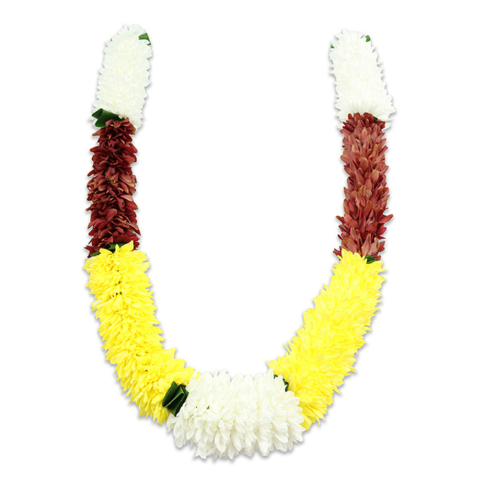 Set against a flat white field, this U-shaped ceremonial garland presents a vivid study in colour, texture and traditional form. The piece is clearly artificial, each bloom a carefully cut and layered fabric petal, packed tightly into cylindrical clusters that begin at the top with creamy white sections resembling small chrysanthemums. These luminous tops transition into compact bands of maroon or reddish-brown, a dense, tactile layer that balances the composition. Extending from there, long, plush sections of bright yellow dominate the lower arcs, their multitude of soft, fluffy petals creating a voluminous, sunlit sweep that visually supports the garland's curve. Where the yellow sections meet at the base, a broader cluster of white chrysanthemum-like flowers anchors the design and serves as the focal point, while touches of dark green leaf elements are placed at the colour joins to add clarity and contrast. The white background and subtle shadowing emphasize the garland's craftsmanship-the precise repetition of thousands of fabric petals and the neat symmetry of the U-shape-suggesting a durable, ceremonial object meant for repeated use. This style of mala is familiar in Hindu ritual and celebratory contexts-puja ceremonies, temple offerings, weddings and festivals-and the chosen palette of white, yellow and maroon carries established meanings of purity, prosperity and devotion. I picture this garland suited to a Catford home altar or a community celebration near the Broadway Theatre, its orderly beauty speaking to both tradition and careful floral workmanship.
